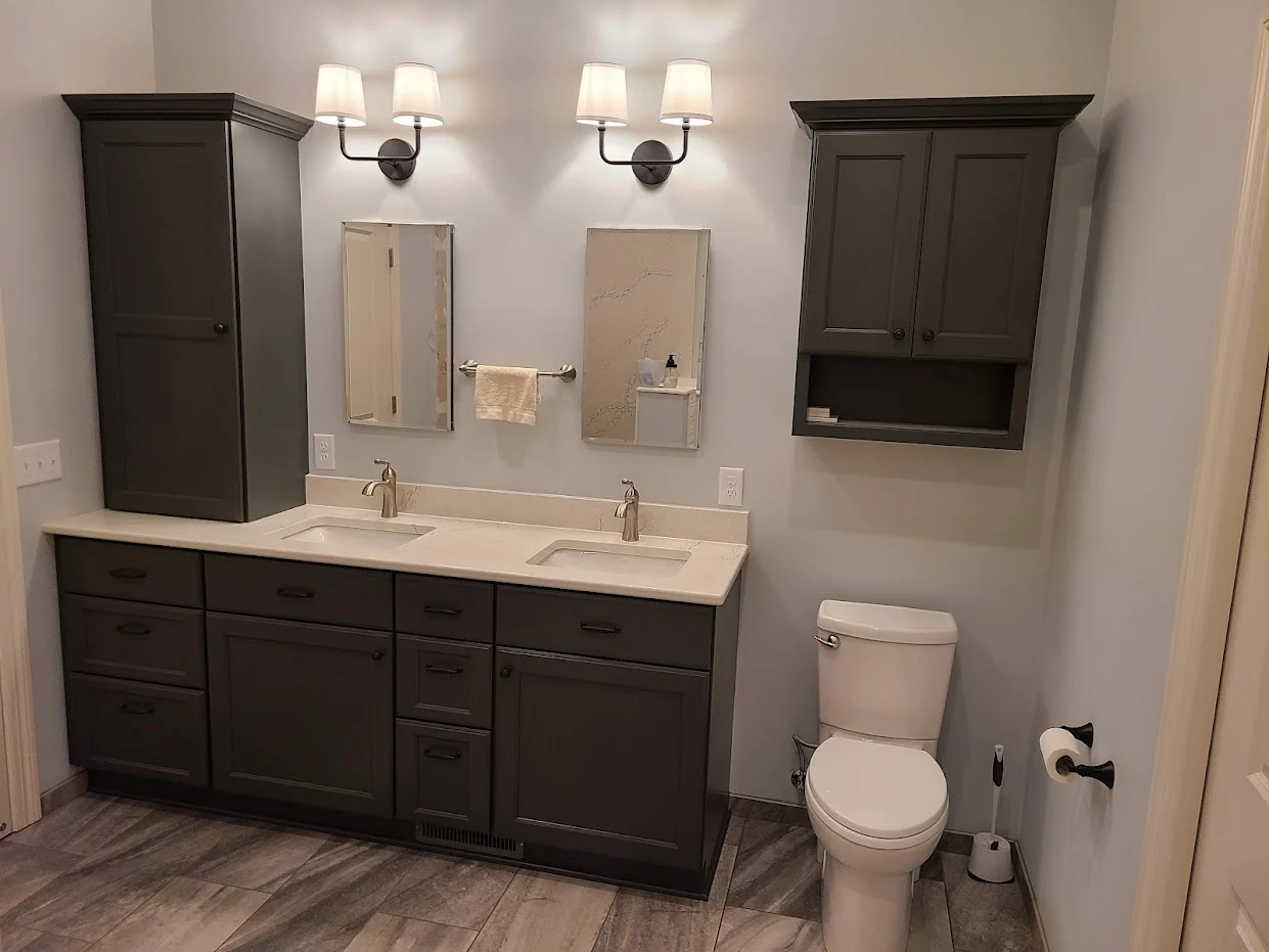 Bathroom with a double vanity, individual mirrors, and wall lighting.