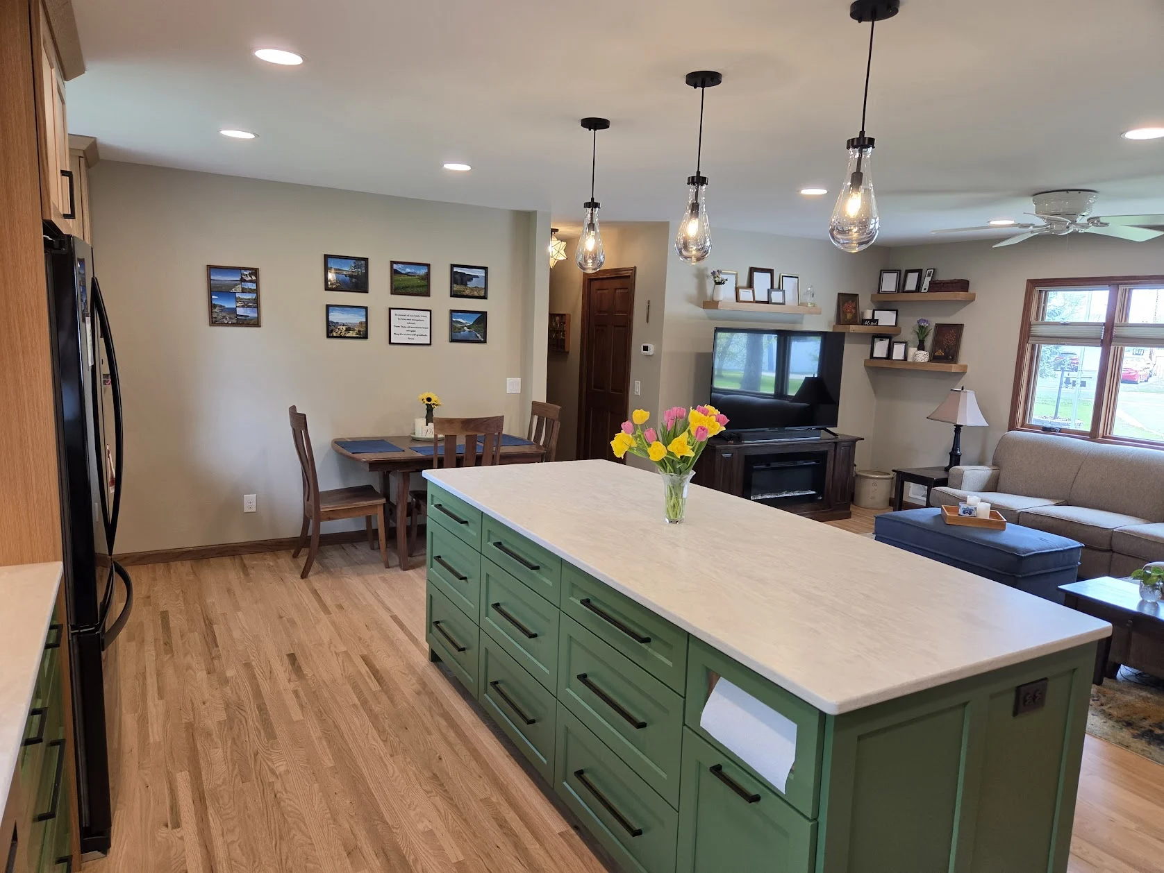 Green cabinetry and natural wood connecting a kitchen and main-level living space