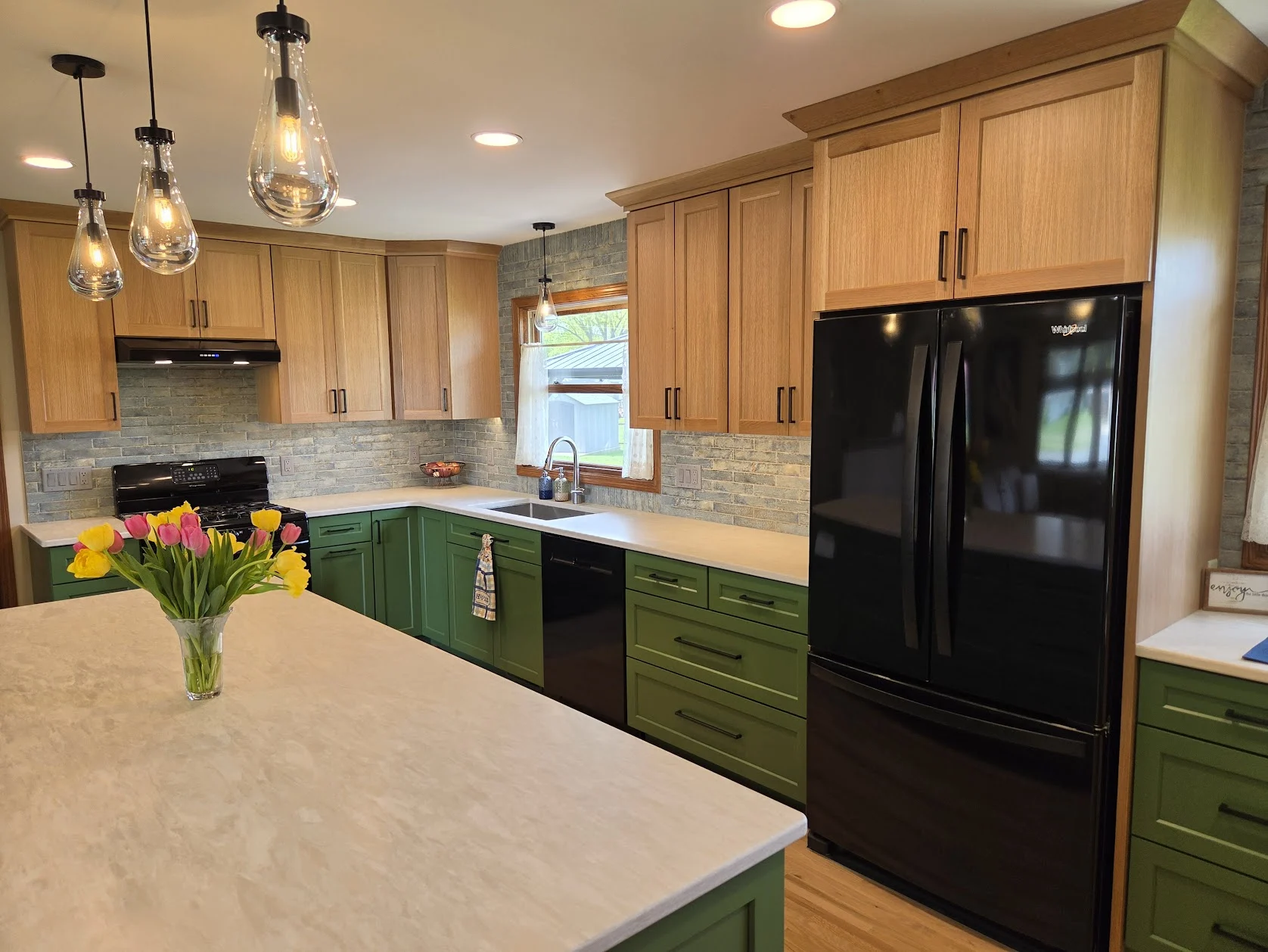 White oak cabinets, soft blue backsplash, and black appliances