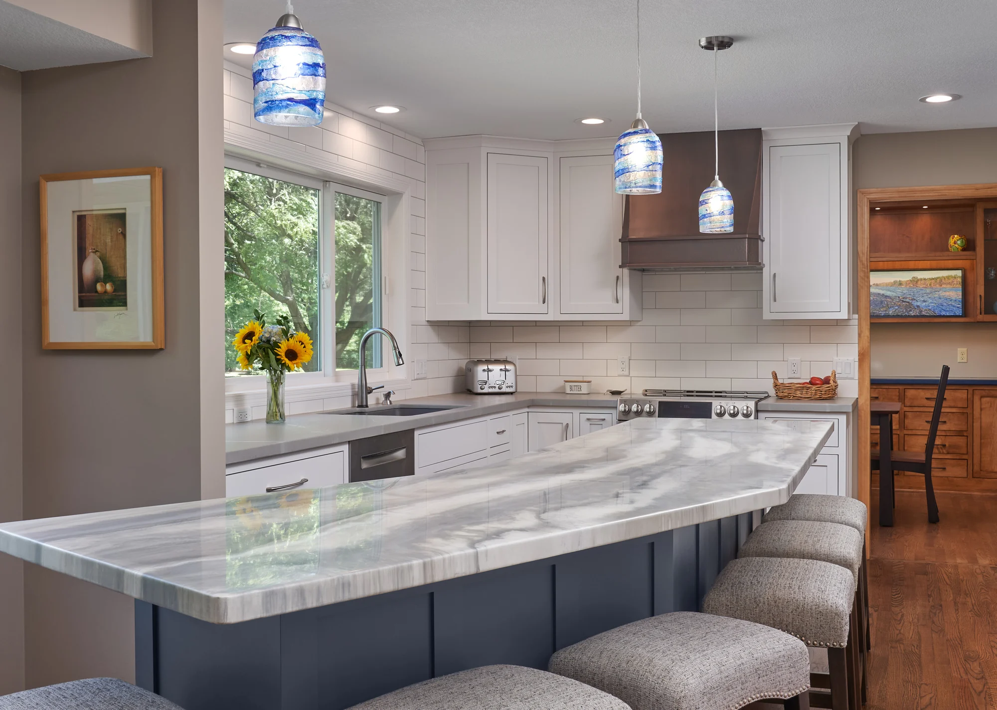 Custom white kitchen with a slate-blue island and copper hood